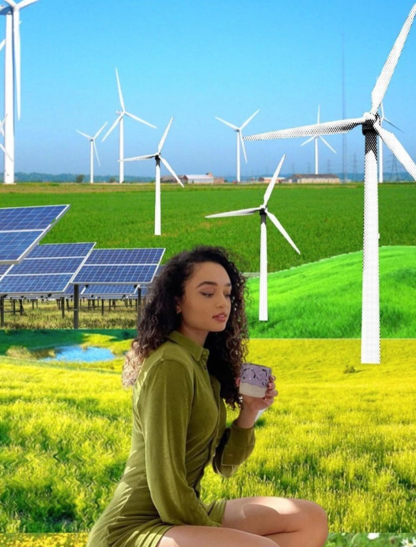 Summer Dean kneeling with a cup of tea with wind mills, solar panels, and fields in the background