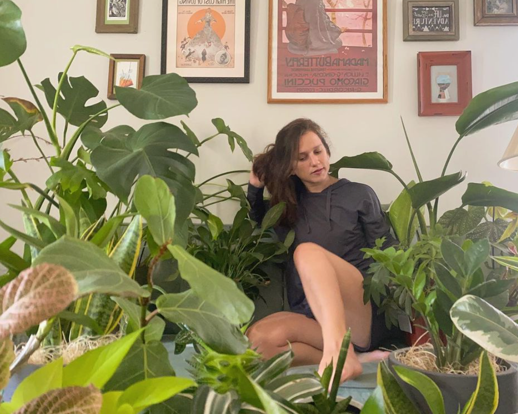 Photo of Femislay on a couch surrounded by plants